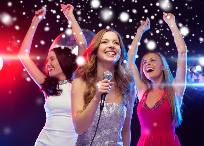 Trois femmes chantent et dansent le karaoké à une fête d'entreprise