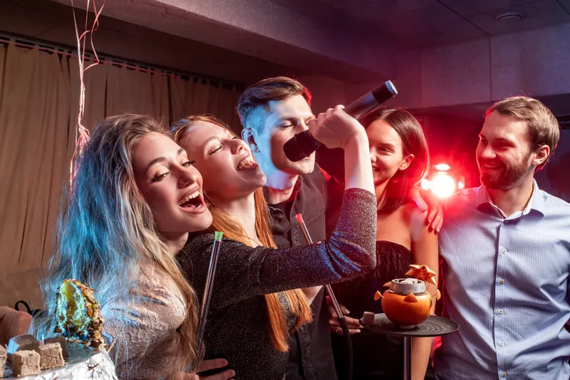 Des amis chantent ensemble au karaoké lors d'une fête privée